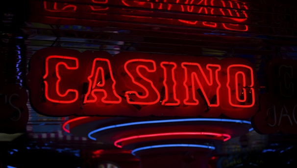 Neon lights display the word 'CASINO' in bright red, standing out against a dark background. The vibrant glow reflects a lively and bustling atmosphere.